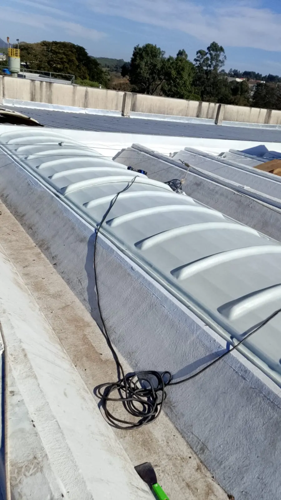 Lanternim com domo translúcido de fibra de vidro instalado na cumeeira de um galpão industrial