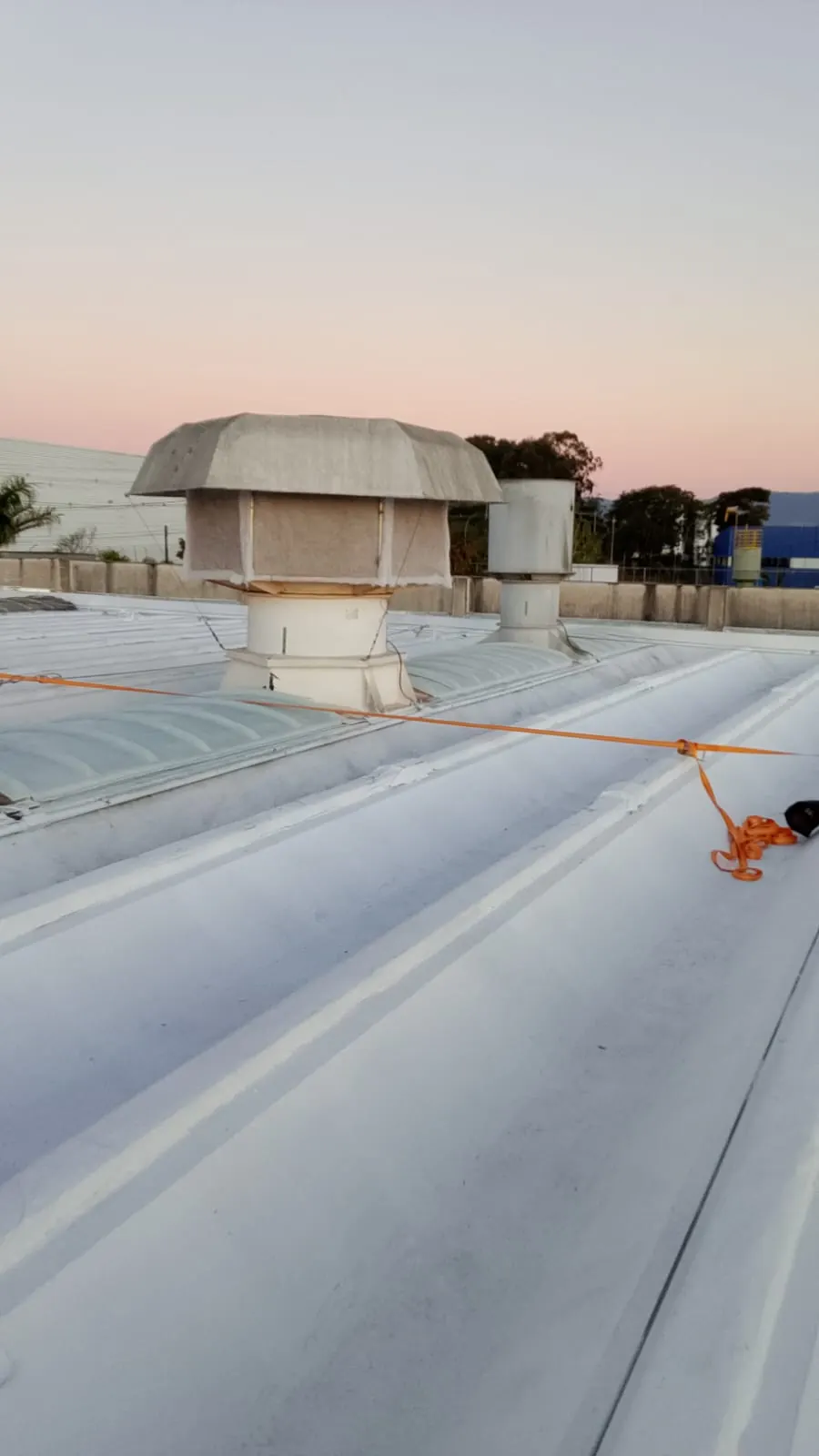 Luz natural entrando pelo domo de fibra de vidro na cumeeira de um telhado metálico no fim da tarde
